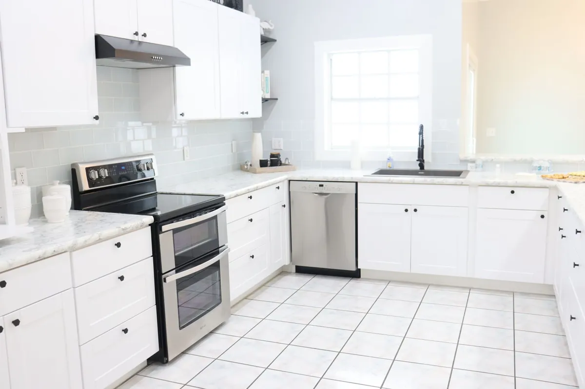 A bright and spacious modern kitchen with white cabinets, appliances, and natural light.