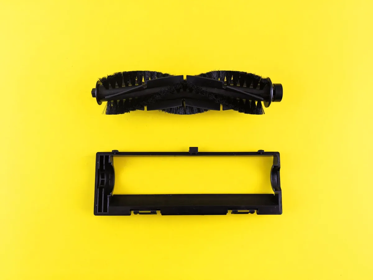 Close-up of vacuum cleaner components on vibrant yellow surface, highlighting maintenance and cleaning.