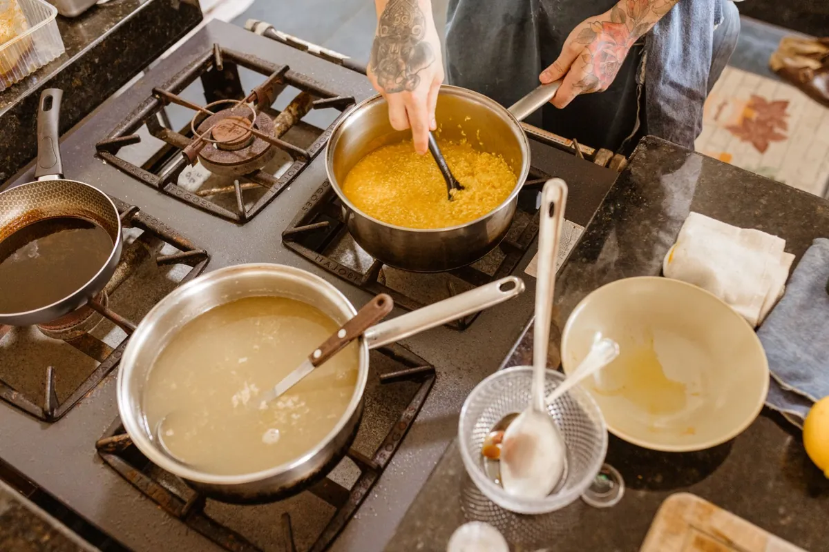 Professional chef stirring ingredients on a gas stove in a modern kitchen setting, showcasing skillful culinary preparation.